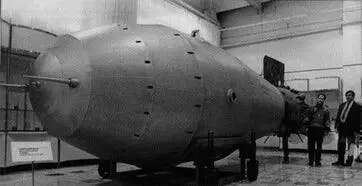 a black and white photo of a huge metal rocket with two men standing behind it to represent the looming risk of inflation getting out of control due to the federal reserve policy