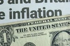 A US one dollar bill lying below a newspaper headline news on inflation.