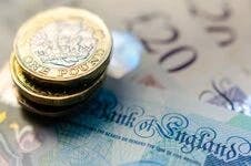 A stack of 1 pound coins and Bank of England notes