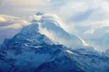 une photo montrant des montagnes bleues entourées de brouillard et de nuages