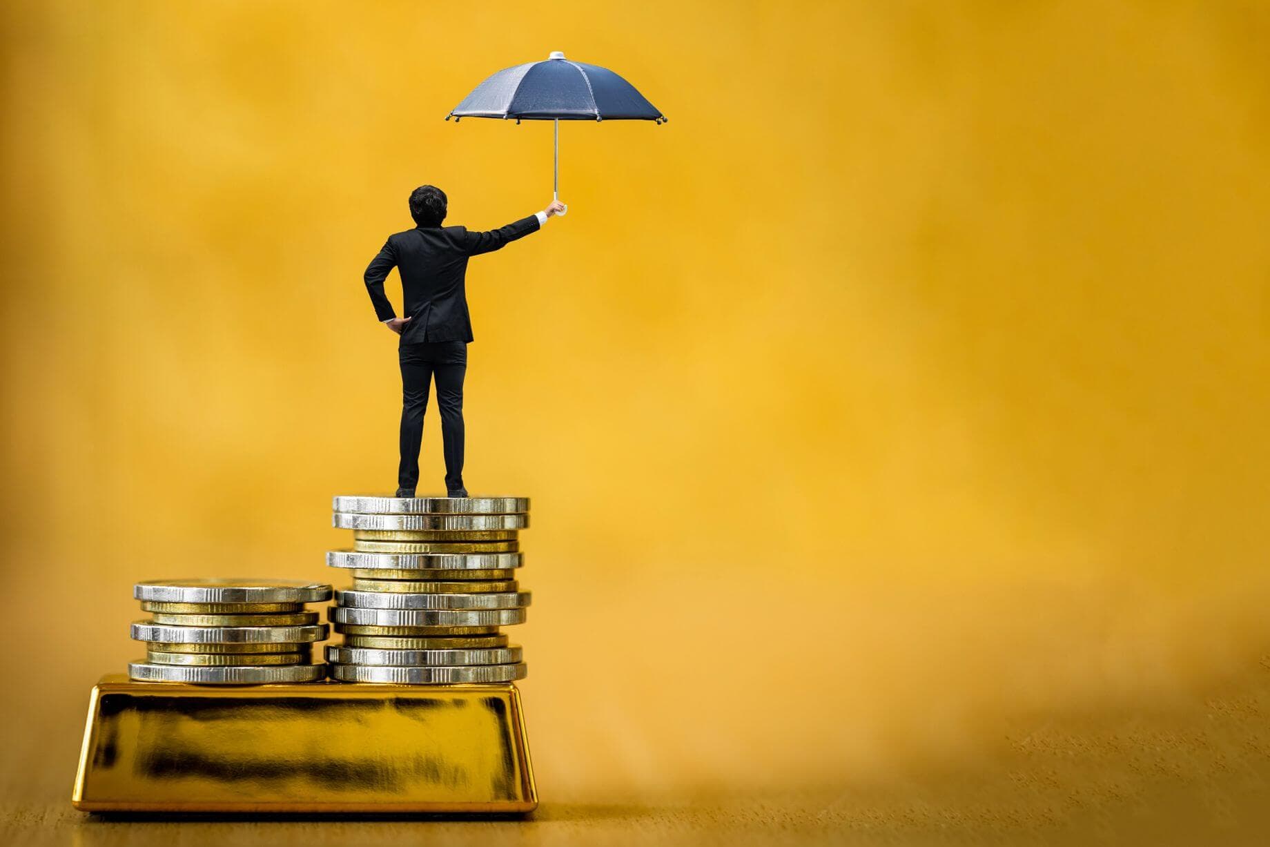 Gold as the ultimate hedge against inflation represented by a picture of a man in a suit standing on a stash of coins Gold as the ultimate hedge against inflation represented by a picture of a man in a suit standing on a stash of coins